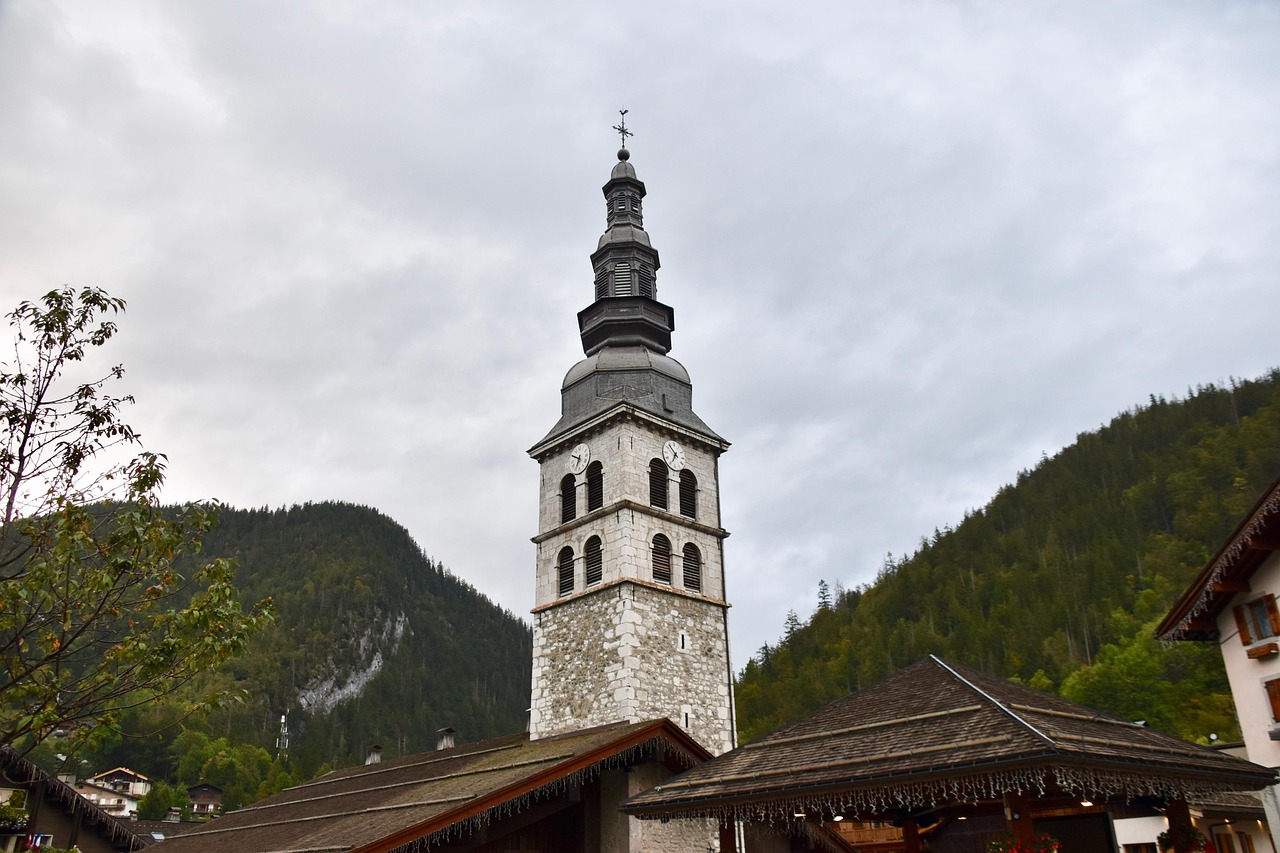 Le clocher de La Clusaz devant les reliefs boisés.
