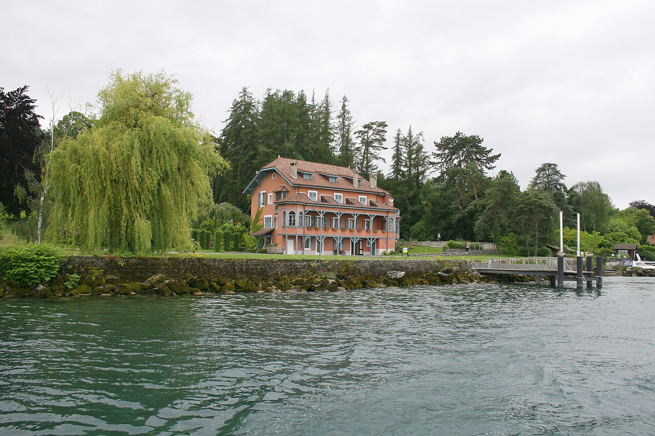 Le jardin du Pré Curieux vu depuis le bateau, avec sa végétation feuillée ; illustration du lieu à la belle saison.